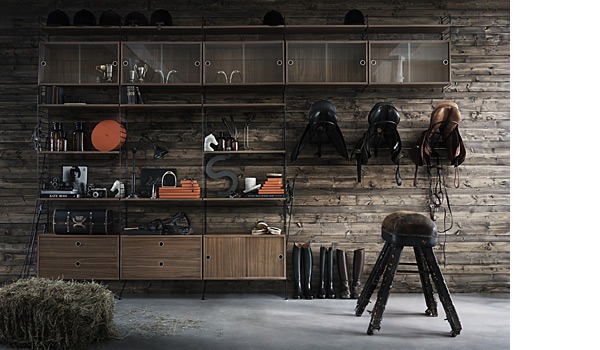 String shelving system. Shown here a with combination of black floor and wall panels with walnut shelves, chests of drawers, normal cabinets and display cabinets.