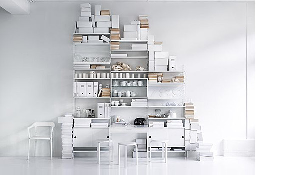 String shelving system. Shown here with a combination of white floor and wall panels with white shelves, cabinets, fold out table and magazin board.